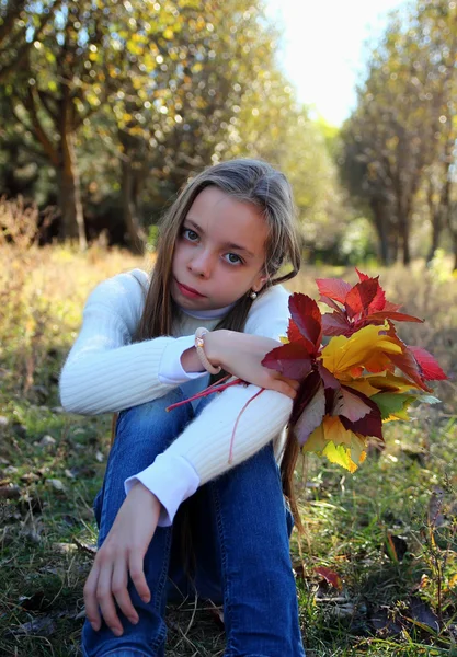 Girl with long hair and a bouquet of autumn leaves — Stock Photo, Image