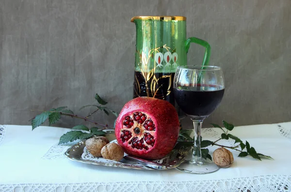 Still Life med granatæble, et glas vin og en kande - Stock-foto