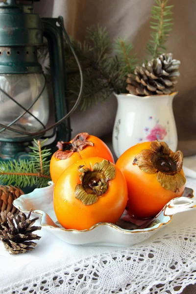 Christmas still life with persimmons and pine cones — Stock Photo, Image