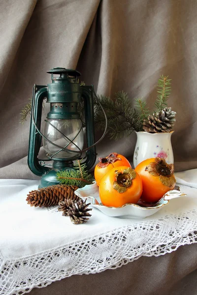 Natal ainda vida com uma lanterna, cáqui e cones — Fotografia de Stock