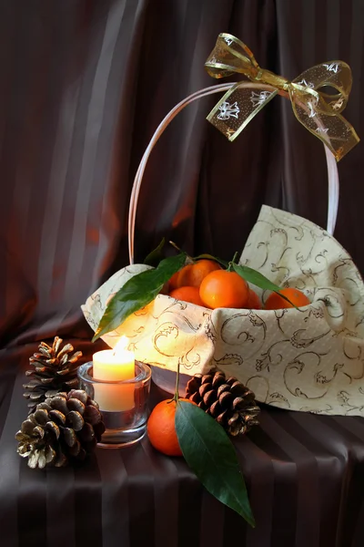 Mandarins in a basket and candle — Stock Photo, Image