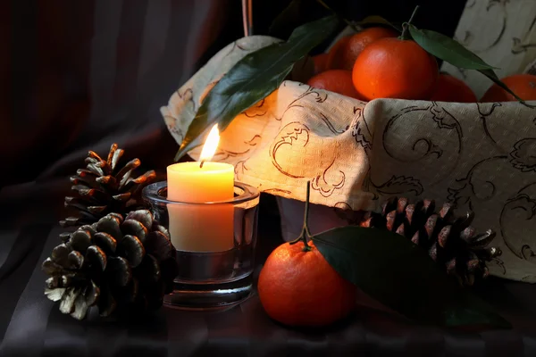 Burning candle and tangerines — Stock Photo, Image