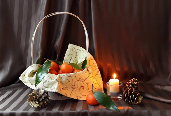 Mandarins in a basket and candle — Stock Photo, Image