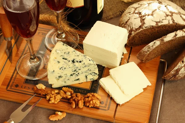 Cheese, glasses of wine and nuts on the board — Stock Photo, Image