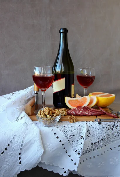 Still life with glasses of wine and a bottle of wine on a white tablecloth — Stock Photo, Image