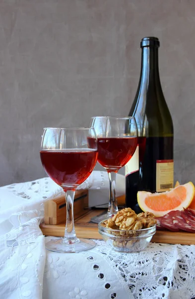 Stilleven met glazen wijn en een fles wijn op een wit tafellaken — Stockfoto