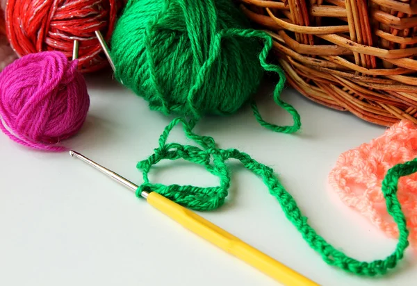 Varias bolas de hilo de colores y un gancho para atar acostado cerca de la cesta — Foto de Stock