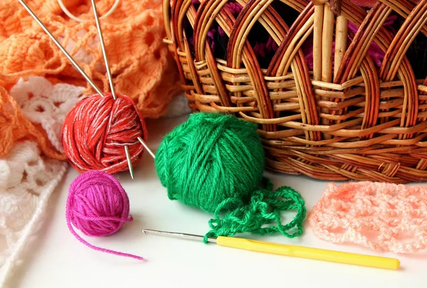 Verschillende ballen uit gekleurde garens en een haak voor koppelverkoop liggen in de buurt van mand — Stockfoto