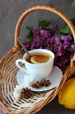 Bir fincan çay ve bir sepet leylak dalı ile