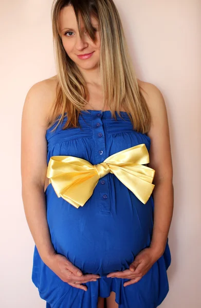 Zwangere vrouw in een jurk met een boog — Stockfoto