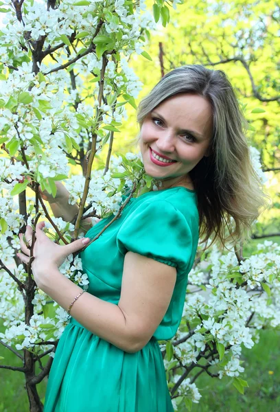 Beautiful girl standing near blooming apple tree — Stock Photo, Image