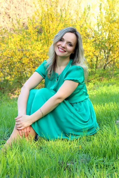 Beautiful girl sitting on the green lawn — Stock Photo, Image