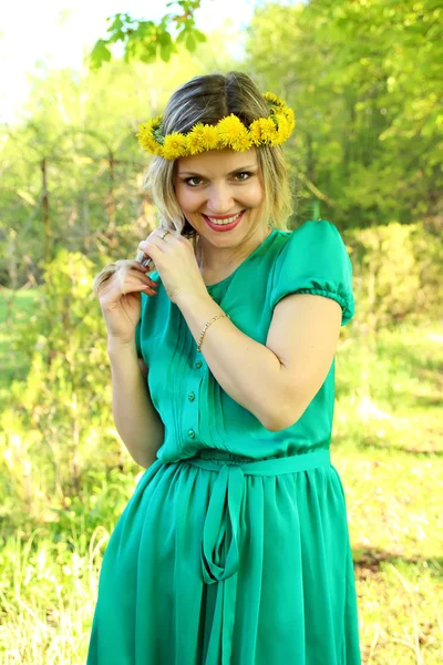 Mooi meisje met een krans van paardebloemen op het hoofd — Stockfoto