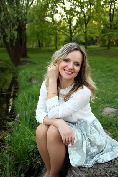 Beautiful girl sitting near the lake — Stock Photo, Image