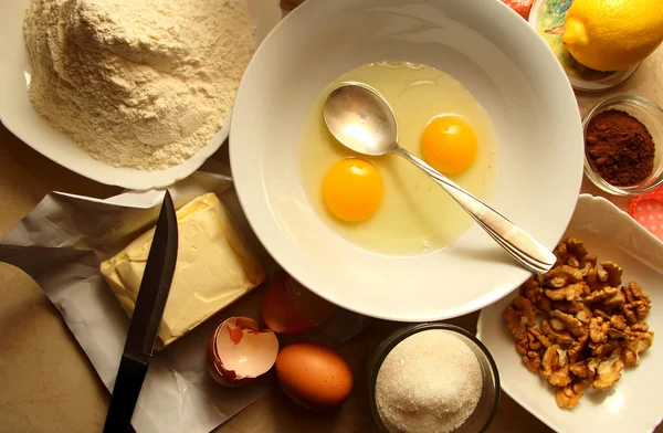 Broken eggs in a dish and the ingredients for the recipe — Stock Photo, Image