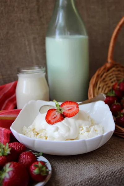 Fat med keso med grädde och jordgubbar och en flaska mjölk — Stockfoto