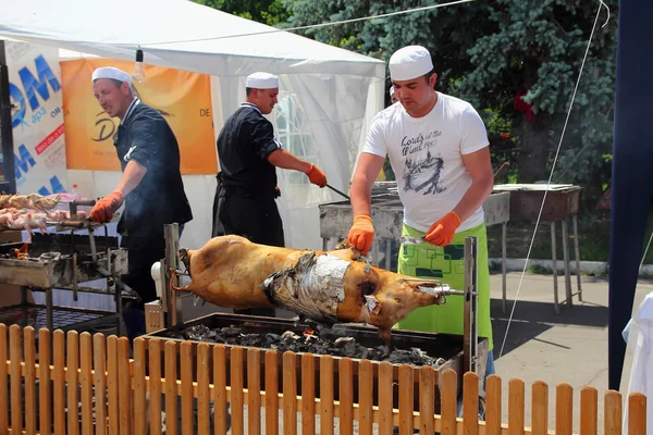 Aşçı ve yardımcıları bir şiş domuz etinin hazırlanması sürecinde — Stok fotoğraf
