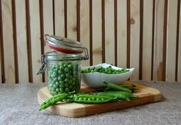 Bank, filled with peas and a plate full of pea — Stok fotoğraf