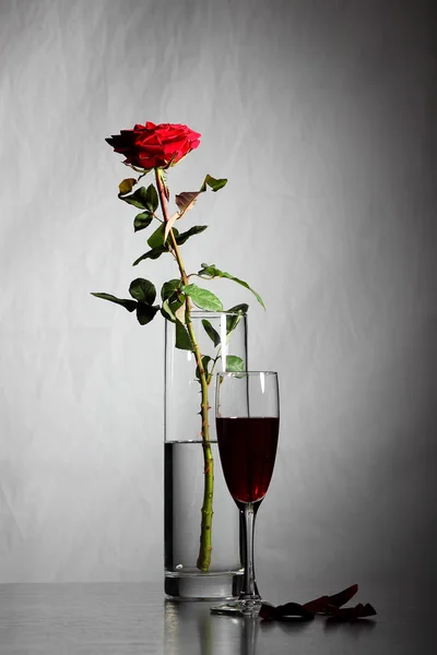 Vaas met rose en glas wijn op de achtergrond van een bakstenen muur — Stockfoto