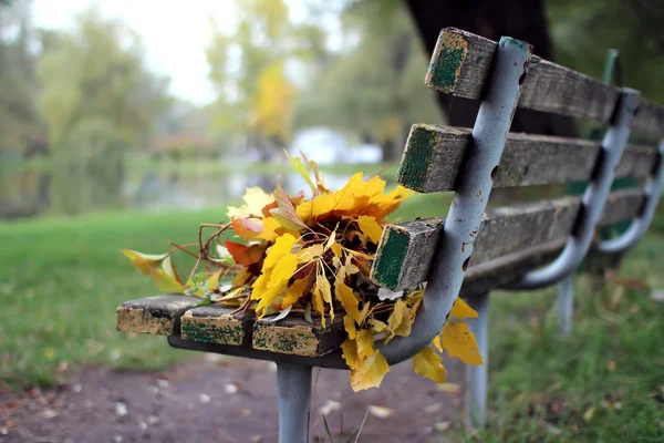 Eine Bank mit einem Strauß Herbstblätter. — Stockfoto