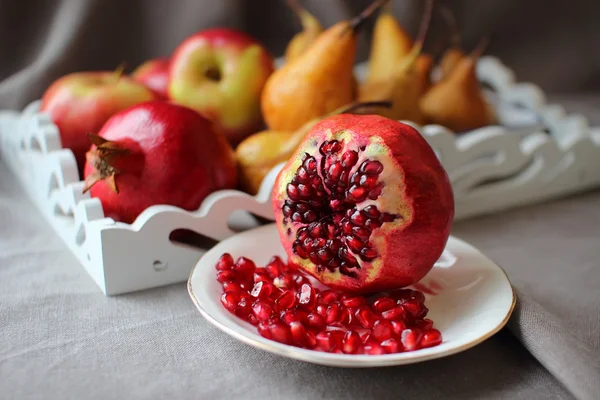 Still life with pomegranates and pear. — Stock Photo, Image