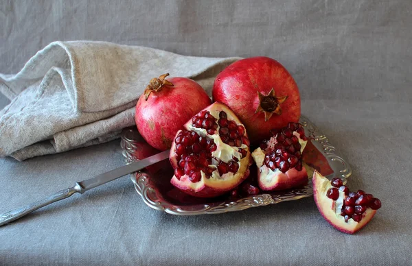 Ripe pomegranate, cut into pieces lying on a plate. — Stock Photo, Image