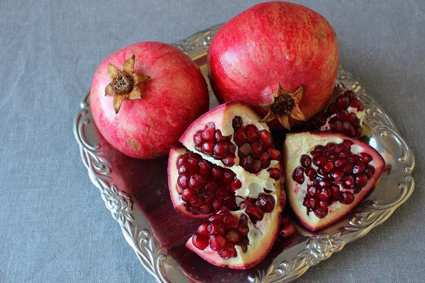 Ripe pomegranate, cut into pieces lying on a plate. — Stock Photo, Image