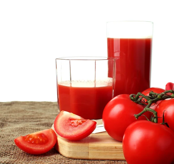 Sumo de tomate despeje em copos e tomates maduros em um fundo branco . — Fotografia de Stock