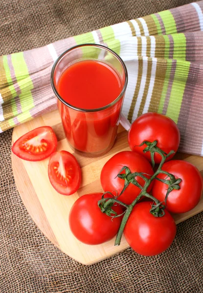 Un vaso de jugo de tomate y tomates maduros . — Foto de Stock
