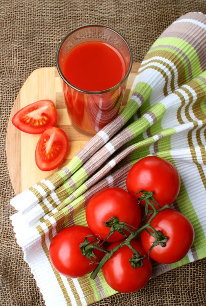 Un vaso de jugo de tomate y tomates maduros . — Foto de Stock