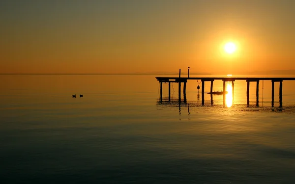 Beautiful sunset on the background of the water surface of the lake. — Stock Photo, Image