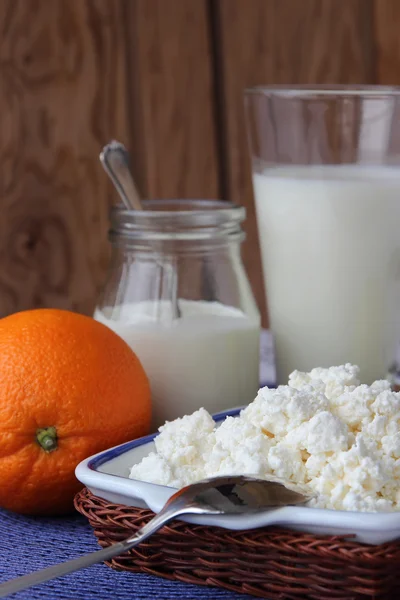 Dish of cottage cheese, a bottle of milk and orange. — Stock Photo, Image