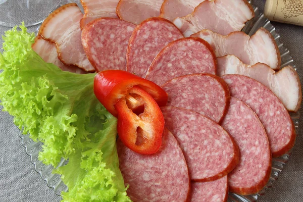 Plate of sausages, decorated with lettuce. — Stock Photo, Image