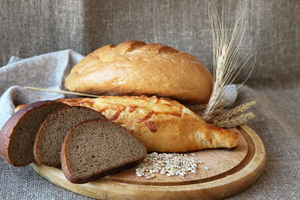 Färskt bröd och olika sorters vete öron. — Stockfoto