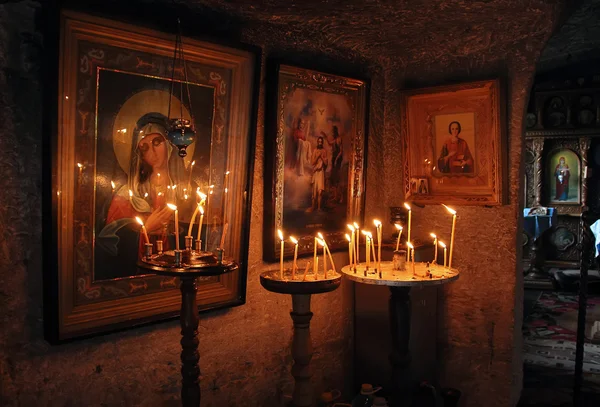 The old icons and burning candles in the rock monastery. — Stock Photo, Image