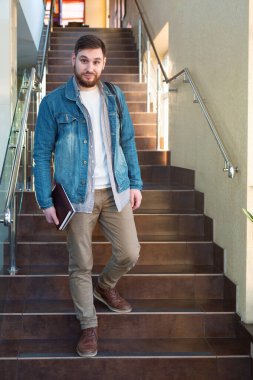 Kahverengi merdivenlerdeki öğrenci. Üniversite kampüs koridorunda sırt çantalı, sırtı sakallı, gülümseyen beyaz adam. Modern çalışma ofisinde serbest çalışan biri..
