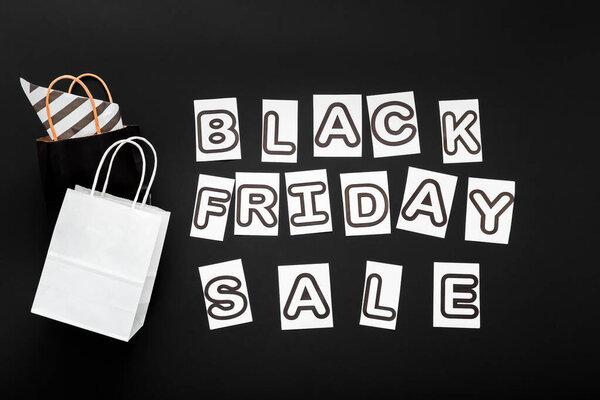 Черная пятница продажи текста буквы с покупками бумажные пакеты на черном фоне. Доставка макет черно-белый пакет бумаги ремесла.
