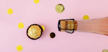 Konfetili bir şişe pembe şampanya, Pembe arka planda altın şeker. Pastel sarısı kutlamalar düzdü. Uzun web pankartı.