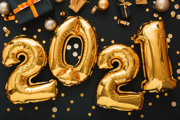 2021 balonlu altın arkaplan, altın renkli konfeti, Noel hediye kutuları, şenlik dekorasyonu. Altın folyo balonları 2021 ile mutlu yıllar arifesi kompozisyonu. Uzun web pankartı