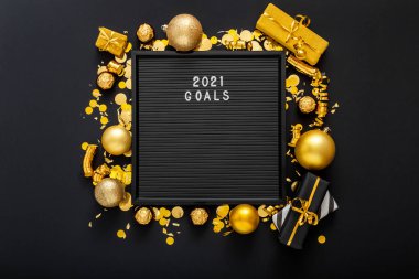 2021 hedef tahtasında altın noel şenliği dekorundan, hediye kutularından ve konfeti toplarından yapılmış bir çerçeve var. Yeni yıl 2021 hedefleri, çözünürlük, motivasyon ve istek listesiyle kontrol listesi. Düz yatıyordu.