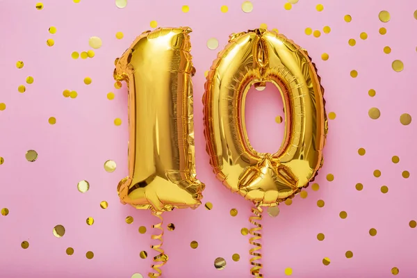 Pembe arka planda 10 hava balonu numarası. Konfetili 20 bin altın folyo. Doğum günü partisi dairesi kopyalama alanı ile yatıyordu.