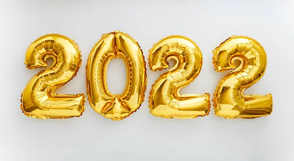 Beyaz arka planda 2022 balon metni. 2022 Noel altın folyo balonları ile mutlu yıllar arifesi davetiyesi. Düz, uzun web pankartı