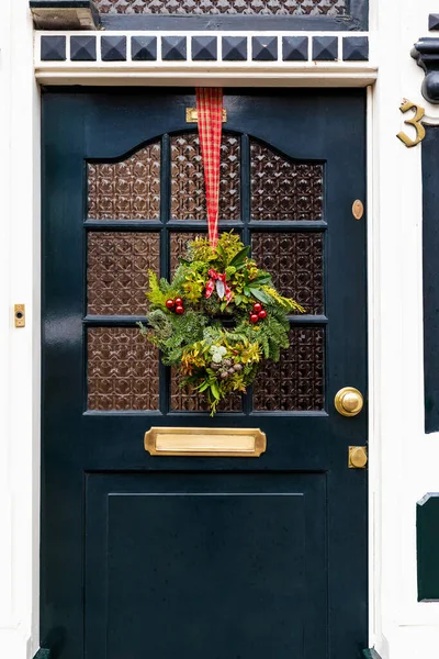 Christmas wreath on entrance vintage door outside. Veranda front door decorated by christmas festive wreath decor. Traditional Christmas exterior in Netherlands.