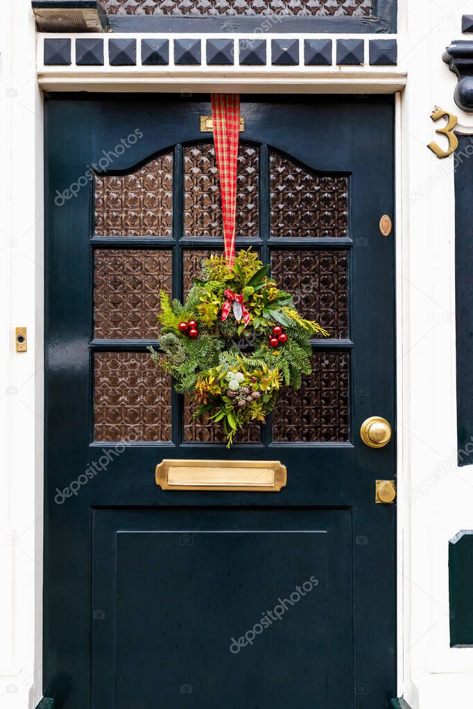 Christmas wreath on entrance vintage door outside. Veranda front door decorated by christmas festive wreath decor. Traditional Christmas exterior in Netherlands.