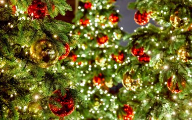 Noel ağacı arka planında ışıklar, şenlikli altın ve kırmızı toplar. Bokeh çelenkleri Noel ağaçlarını süslerdi. Yılbaşı ağacının ışıkları. Sokak Avrupa Fuarı.