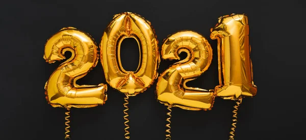 Siyah arka planda 2021 balon altın metin. 2021 noel altın folyo balonlarıyla mutlu yıllar arifesi davetiyesi. Uzun web pankartı