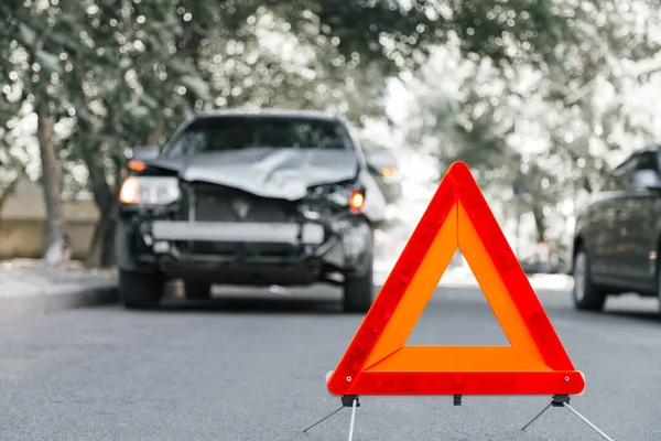 Piros vészleállító háromszög jelzés az úton egy autóbalesetben. Egy összetört terepjáró közúti balesetben. Autóbaleset a városi úton ütközés után — Stock Fotó