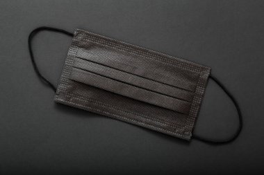 Siyah tıbbi maske. Siyah arka planda, ağzı ve burnu kaplayan tek kullanımlık koruyucu yüz maskesi. Coperid 19 'u, Coronavirus' u önleyin. Sağlık karantinası, kilit altında hijyen konsepti