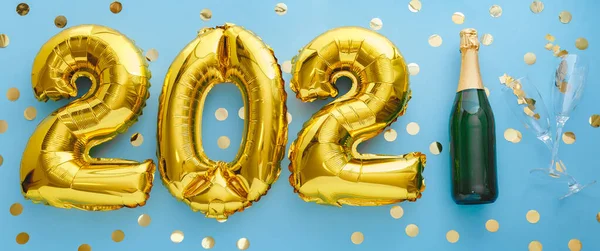 2021 golden air balloon numbers on blue background bottle of champagne and glasses with confetti. Happy New year eve invitation card with Christmas gold foil balloons 2021. Flat lay long web banner — Stock Photo, Image