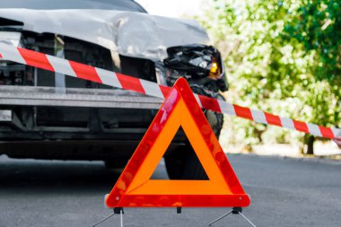 Polis şeridi ve trafik kazasının önündeki yolda kırmızı acil durum üçgeni işareti. Trafik kazasında kırık bir SUV arabası. Çarpışmadan sonra şehir yolunda trafik kazası.